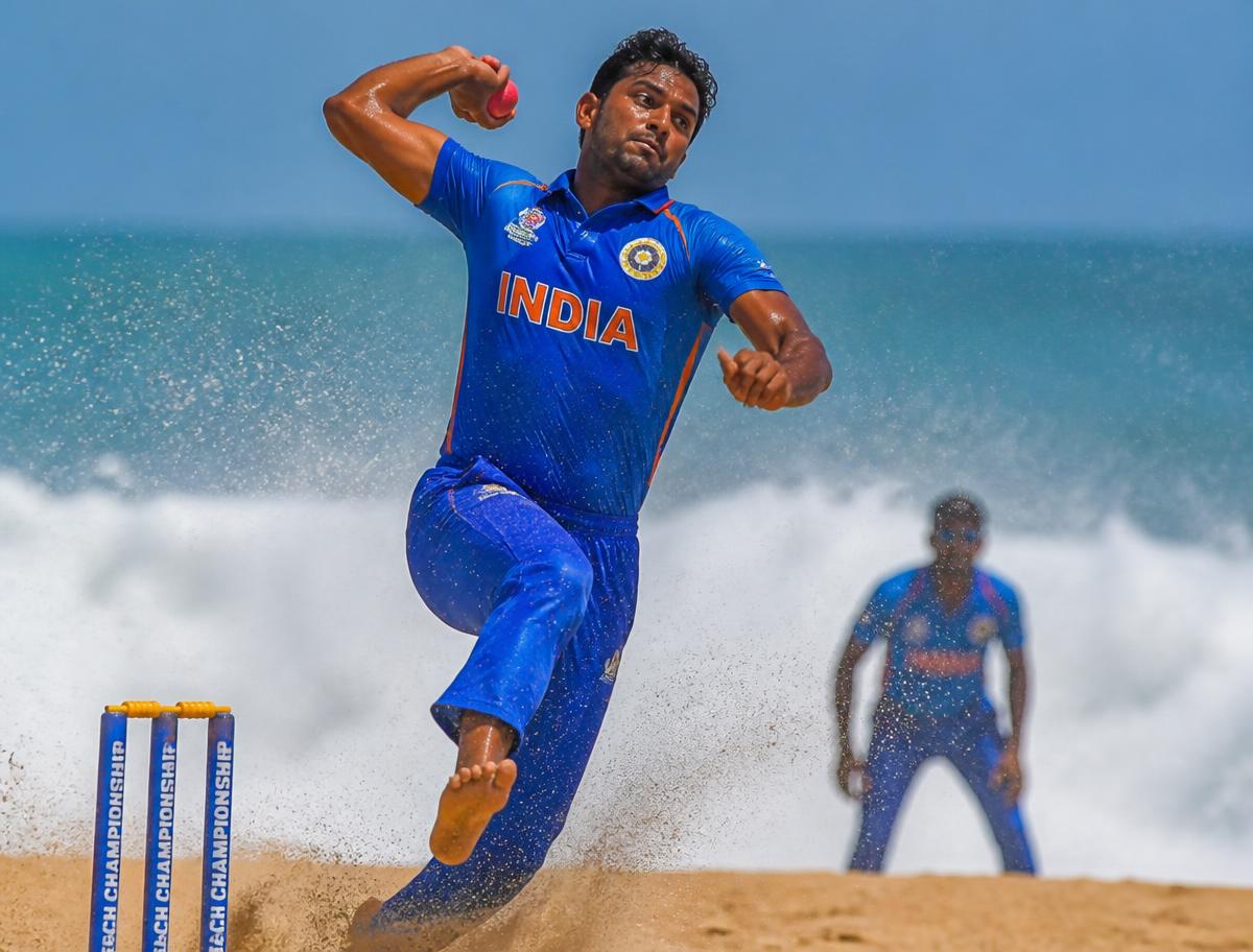 Beach cricket fast bowler leaping in delivery stride on sand